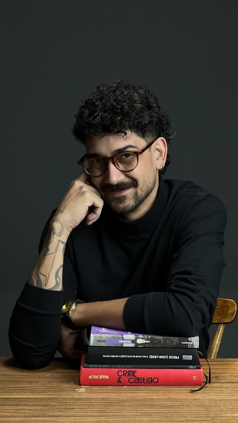 Leonardo Rodrigues apoiado em uma pilha de livros
